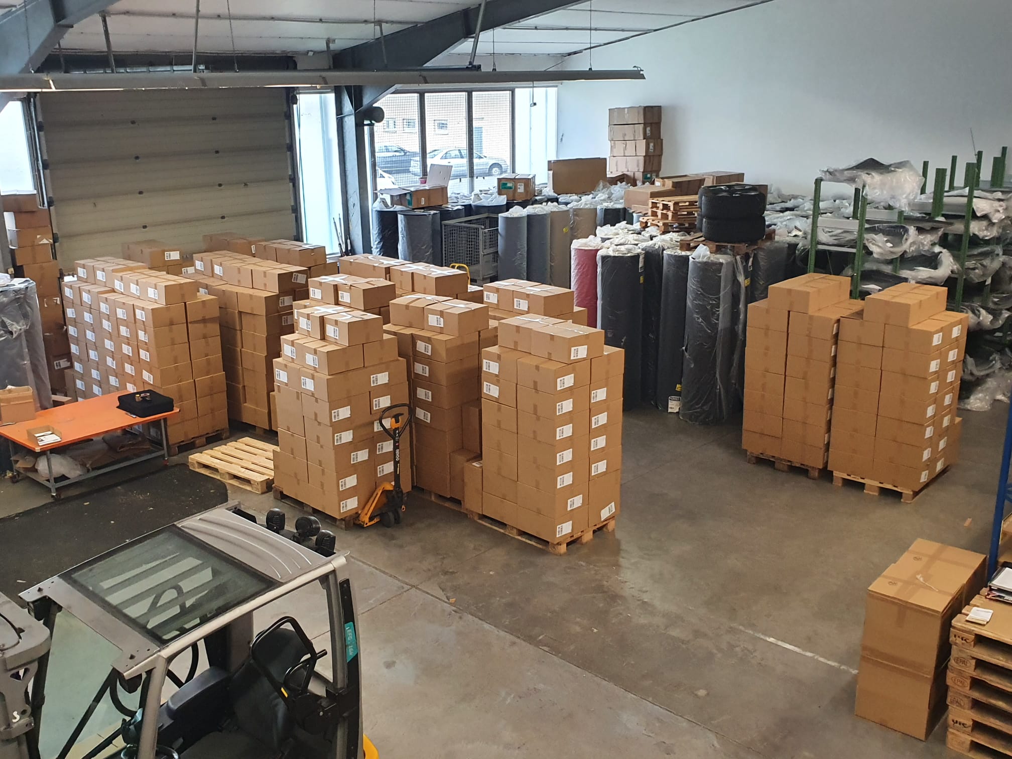 Lager Foto Hunderte fertige Pakette, Teppichrollen und ein Stapler im Lager von Autoteppich-Stylers.